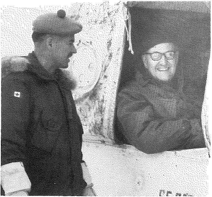 Two men in winter parkas outdoors, one in a beret facing the other, whose face is framed by a fur-trimmed hood.