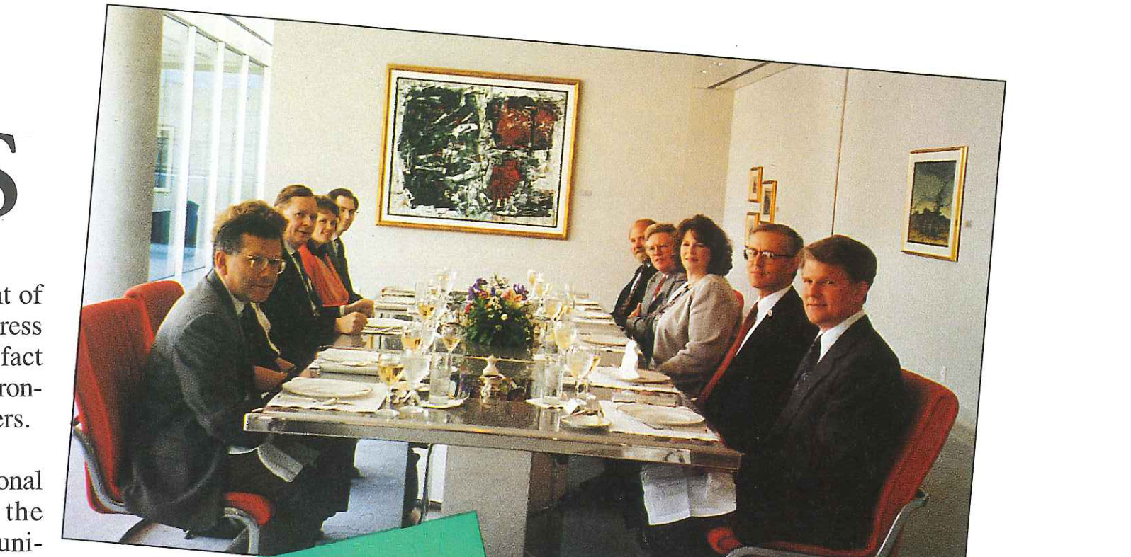 People seated around a long table set for lunch in a panelled room.