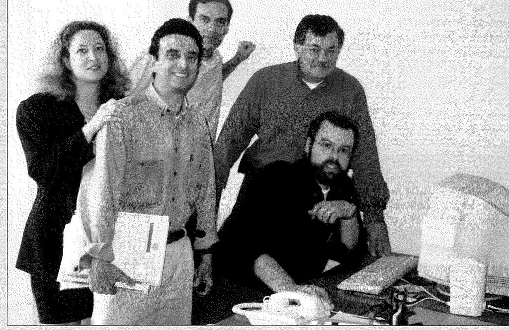 Five colleagues standing together behind an office desk