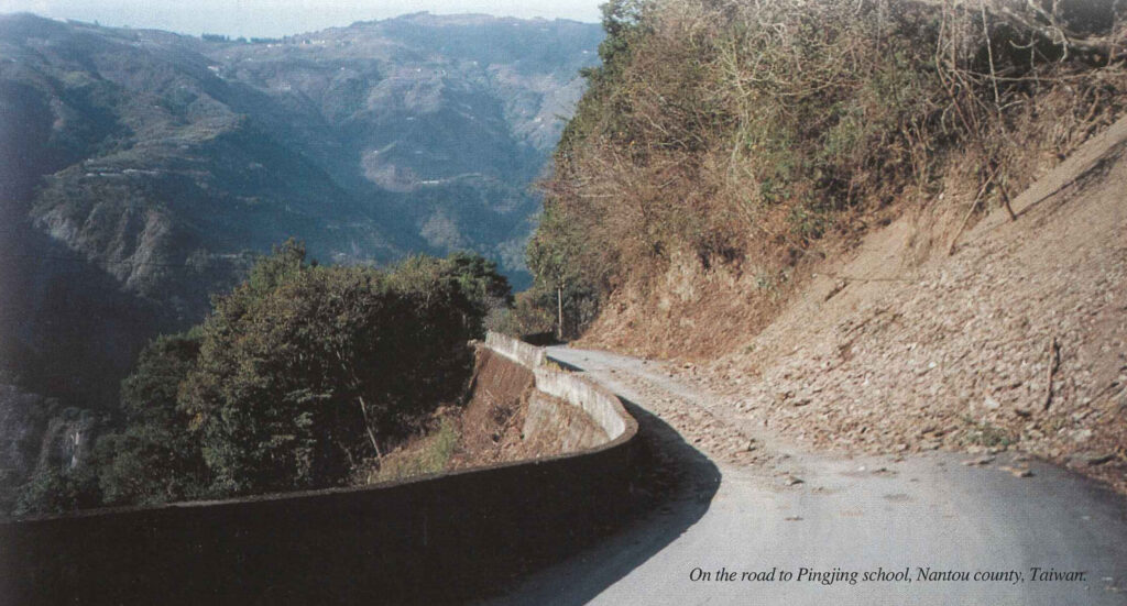A gravel mountain road curving round a steep forested hillside above a valley
