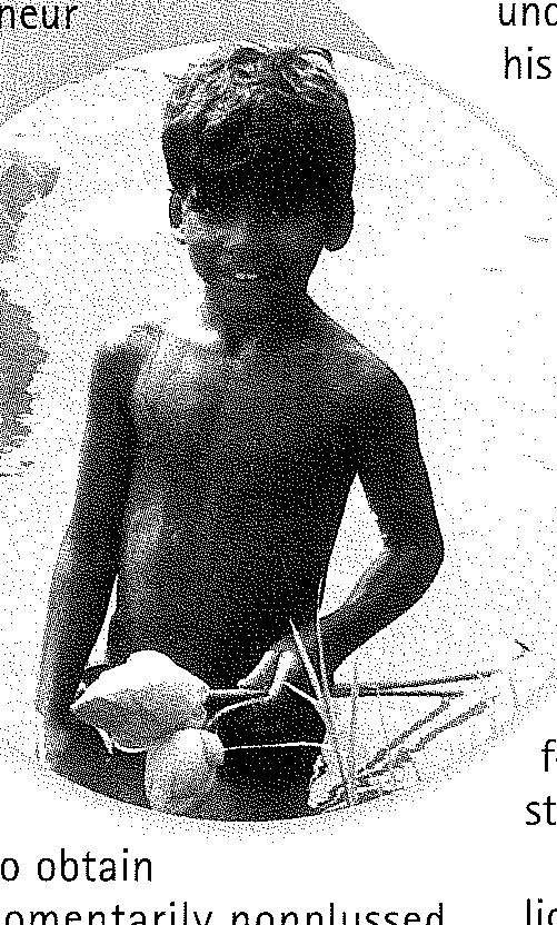 A bare-chested young boy holding lotus blossoms and their stems in front of him.