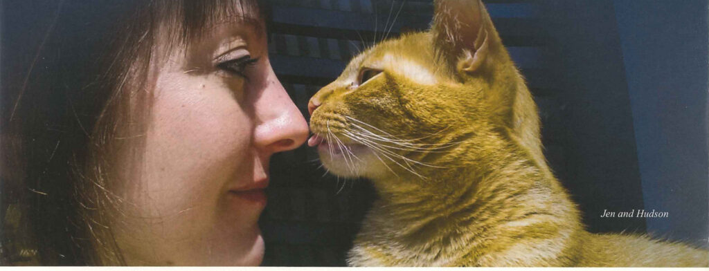 A woman kneeling nose to nose with a ginger cat
