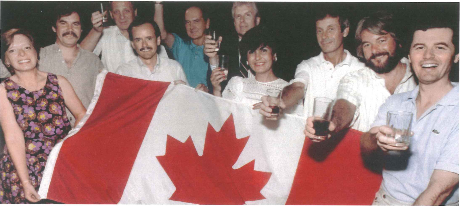 A group of men and women raising glasses together in a crowded room