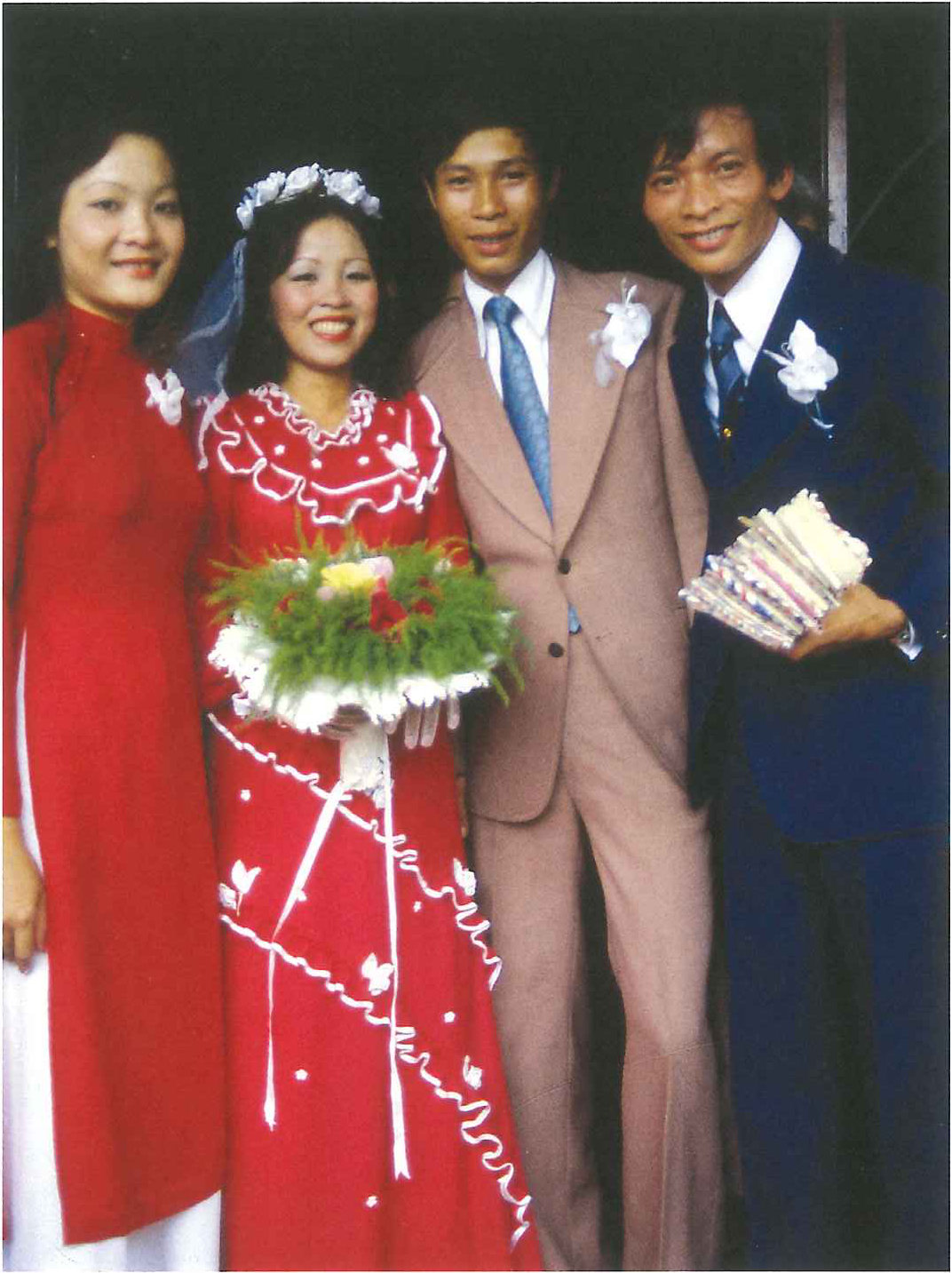 A bride in red and three others posed for a wedding photograph, holding a bouquet