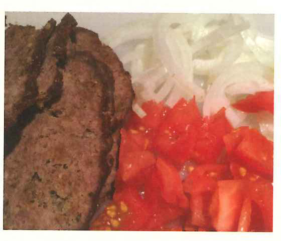 Slices of spiced ground-beef loaf with chopped tomato and sliced onion